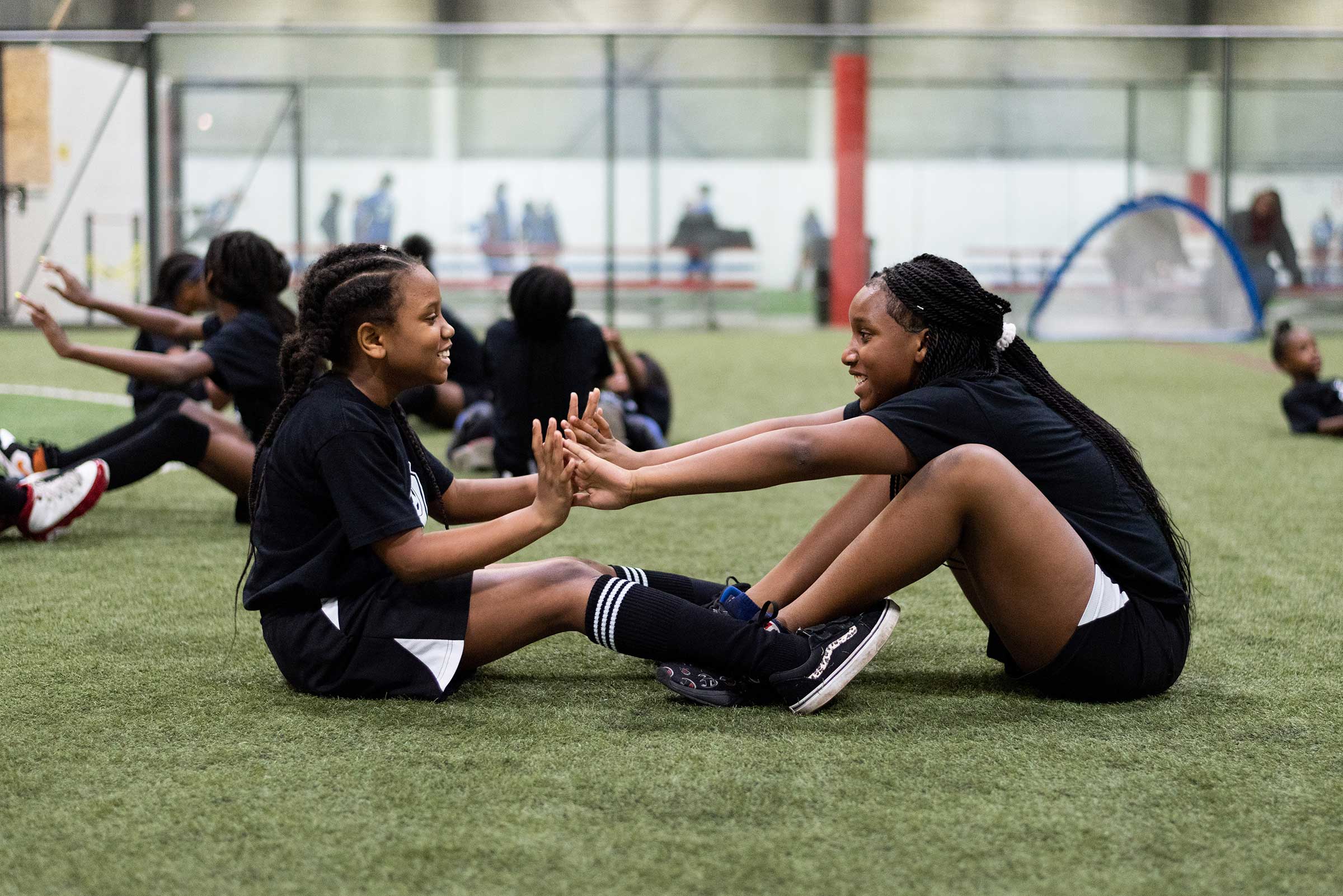 Two girls stretching before a soccer game